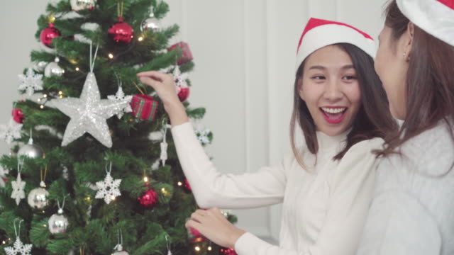 Gruppe-von-fröhlich-glücklich-junge-asiatische-Frauen-Weihnachten-Geschenke-miteinander-in-ihrem-Wohnzimmer-zu-Hause-in-Christmas-Festival.-Lifestyle-Frauen-feiern-Weihnachten-und-Neujahr-Konzept.