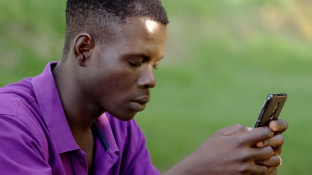 se-centran-en-la-juventud,-comunicación,-tecnología.-Hombre-joven-negro-utilizando-smartphone-outdooor