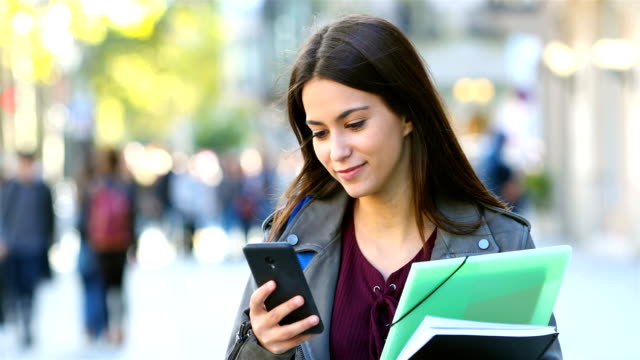 Student-walking-and-checking-phone-in-the-street