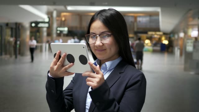 Asiatische-Geschäftsfrau-arbeiten-an-digital-Tablette-am-Flughafen