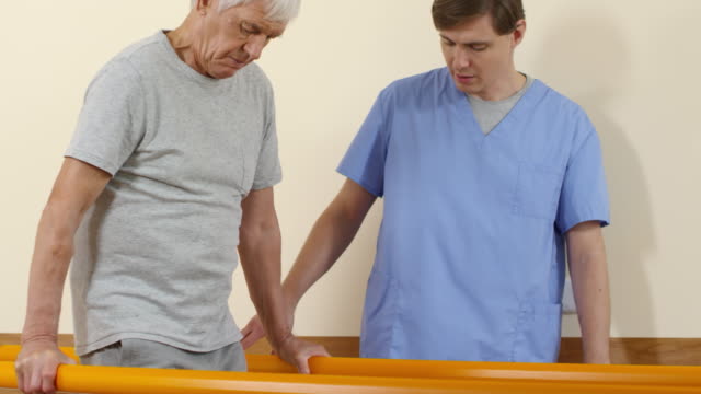 Physiotherapeuten-unterstützen-ältere-Mann-lernen,-zu-Fuß