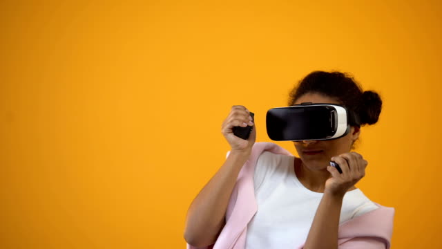 Afro-american-woman-in-virtual-reality-glasses-playing-games,-motion-controllers