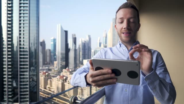 Caucasian-man-using-digital-tablet-for-internet-and-communications-with-cityscape-background