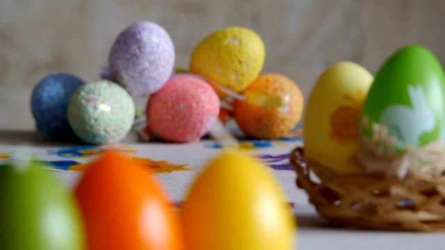 Close-up.-Candles-made-in-shape-of-easter-egg.-Easter-eggs-candles-and-colorful-Easter-eggs-in-the-background.-Refocusing.
