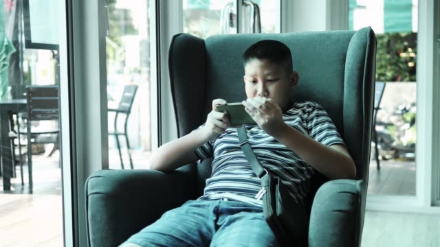 Junger-Teenager-spielt-auf-Smartphone-im-Café