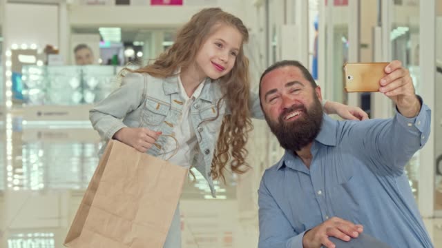 Entzückende-kleine-Mädchen-machen-Selfies-mit-ihrem-Vater-in-der-Shopping-Mall