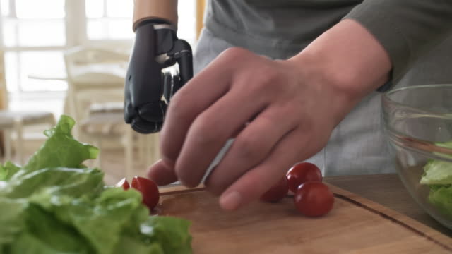 Mann-mit-myoelektrischen-Prothesen-arm-schneiden-Tomaten