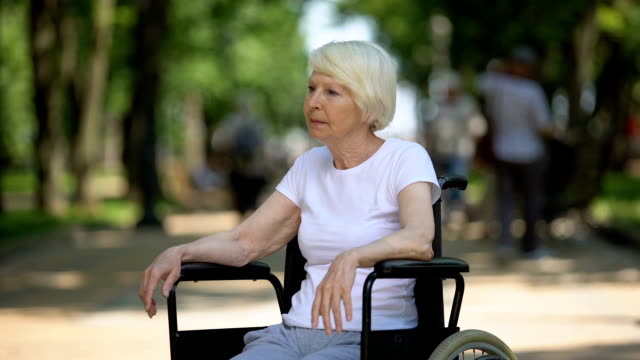 Verärgerte-ältere-Frau-sitzt-im-Rollstuhl-im-Pflegeheimpark,-tödliche-Krankheit