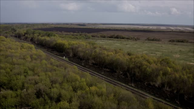 A-railway-track-passing-through-the-forest-and-field.-Shooting-from-a-height.