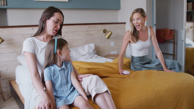 Same-Sex-Female-Couple-At-Home-In-Bedroom-Getting-Daughter-Ready-For-Schoolæ