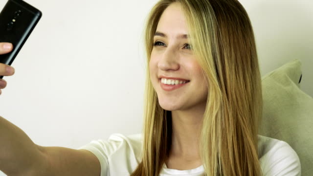 Beautiful-blonde-woman-looking-at-her-cell-phone,-taking-a-selfie-in-a-cafe.-4K