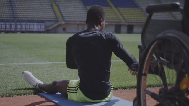 Athlete-sitting-on-ground-and-warming-up