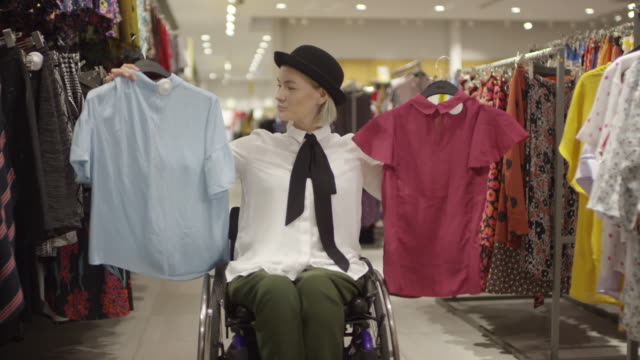 Behinderte-Frau-im-Rollstuhl-Wahl-Shirts-im-Laden