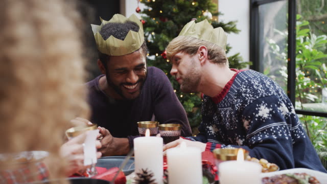 Pareja-masculina-gay-sentada-alrededor-de-la-mesa-para-la-cena-de-Navidad-hablando-y-haciendo-un-brindis