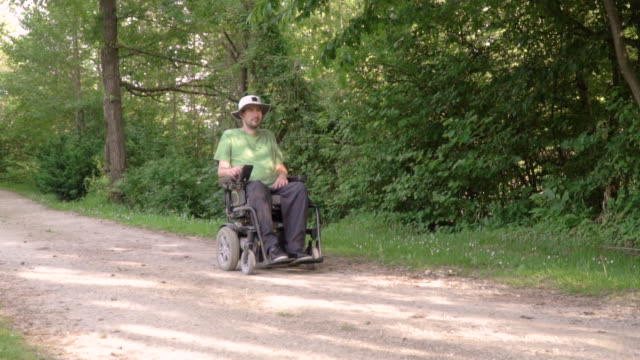 Slowmotion-follow-of-disabled-young-man-in-a-wheelchair-observing-nature-around-him