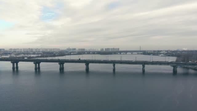 Verkehr-auf-einer-Brücke-über-einen-breiten-Fluss-im-Winter