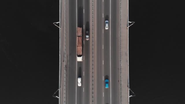 Timber-truck-on-bridge-highway-in-traffic-aerial-top-view