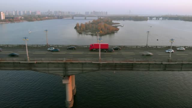 Red-truck-rides-on-a-road-bridge-over-a-river