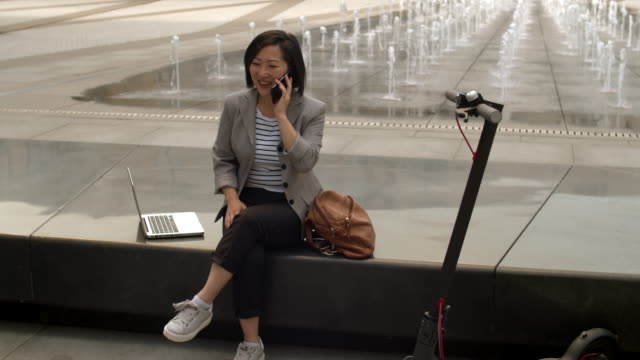 Asiatische-Frau-mit-Telefongespräch-im-Freien