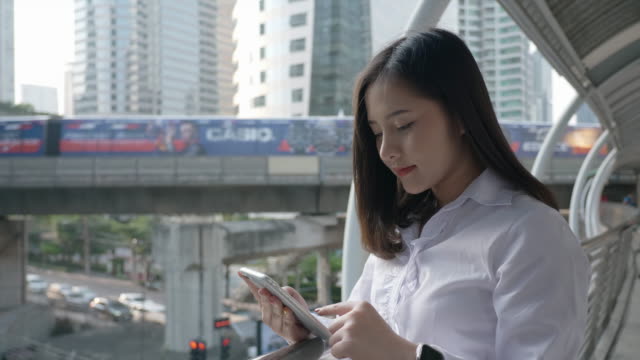 Seitenansicht-der-Aufgeregten-Business-asiatische-Frau-feiert-gute-Nachrichten-überprüfen-Smartphone-in-der-modernen-Stadtzentrum-von-Bangkok-Thailand.-Konzept-Technologie-Kommunikation,-Erfolg-per-Handy