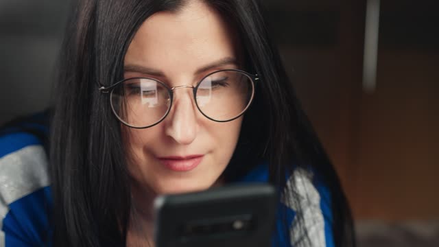 Close-up-pleasant-girl-in-glasses-looking-at-screen-of-smartphone.-4k-Dragon-RED-camera