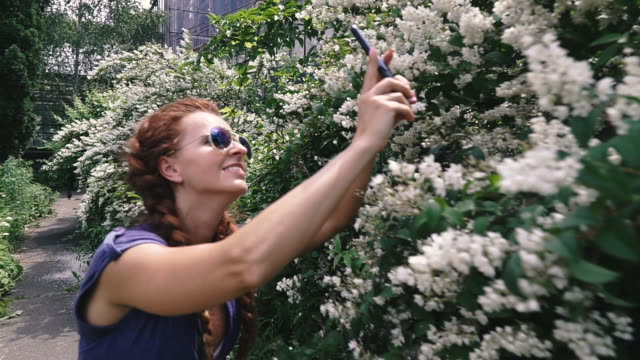 Smartphone.-Una-joven-toma-flores-en-un-teléfono-inteligente.