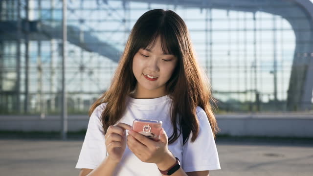 Attraktives-Porträt-von-jungen-asiatischen-angenehmen-Frau-zu-Fuß-mit-dem-Smartphone-in-der-Nähe-von-modernen-Flughafen