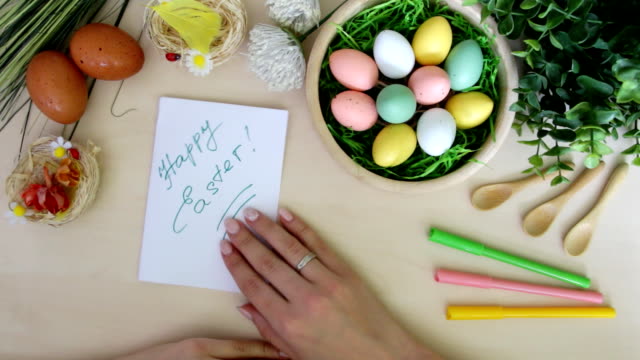 Hand-with-marker-doing-postcard-and-Easter-decorations-on-wooden-background