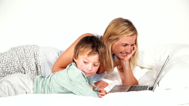 4-year-old-boy-lies-with-his-mother-in-bed-and-plays-with-notebook