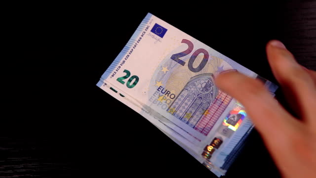 Jemand-legt-Pack-20-Euro-Banknoten-auf-den-schwarzen-Tisch