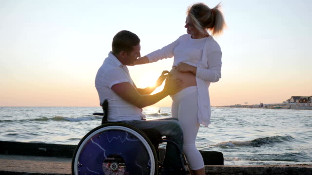 verkrüppelte-Liebe,-trächtige-Weibchen-mit-ungültigen-Mann-im-Rollstuhl-bei-Sonnenuntergang
