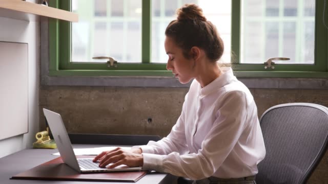 Woman-reading-document-and-using-laptop-in-office,-close-up