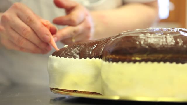manos-de-chef-de-pastelería-decorar-tortas-de-pan-dulce-de-Pascua-con-pastelera,-closeup-en-la-encimera-en-confitería