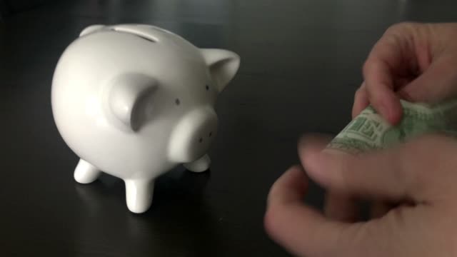 Frau,-eine-US-Dollar-Banknote-in-ein-Sparschwein