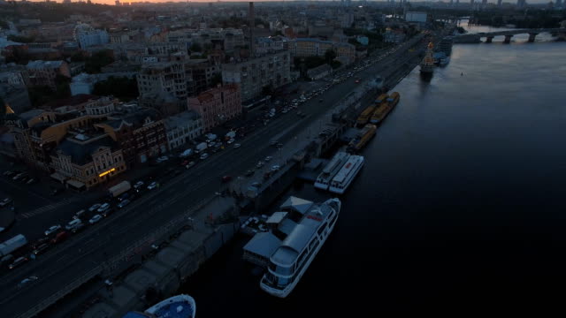 Traffic-jam-on-the-road-along-the-river-with-boats-at-sunset-aerial