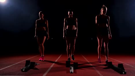 Female-runners-at-athletics-track-crouching-at-the-starting-blocks-before-a-race.-In-slow-motion