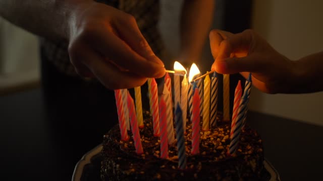 Woman-and-man-lights-candles-on-tasty-birthday-cake.-Prepearing-for-party