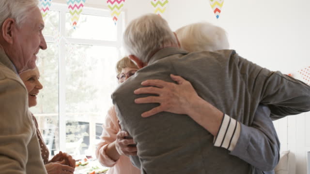 Happy-Senior-Woman-Greeting-Guests-at-Home