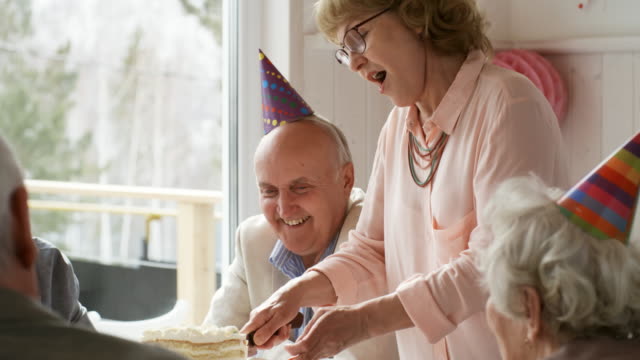 Senior-Lady-schneiden-süßen-Kuchen-zum-Geburtstag-Abendessen