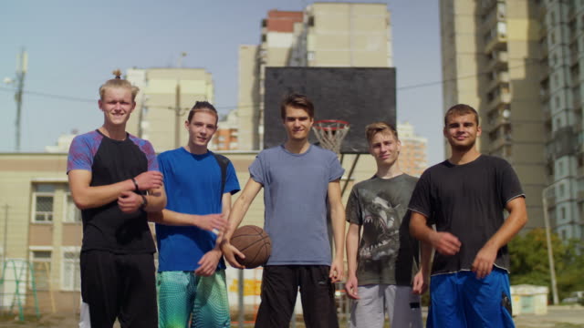 Smiling-streetball-players-with-basketball-on-court