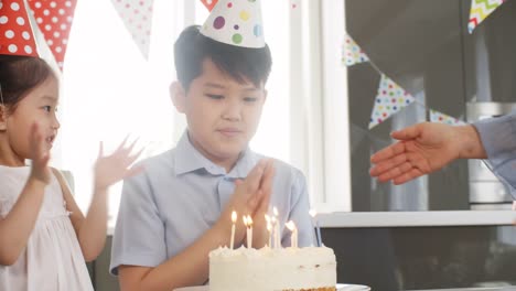 Mädchen-helfen-Bruder-Blowing,-Kerzen-auf-Kuchen