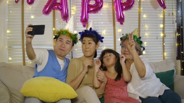 Retrato-de-joven-familia-asiática,-relajarse-y-tomar-fotos-selfie-en-sofá-en-casa.-Familia-feliz-disfrutando-de-tiempo-juntos.