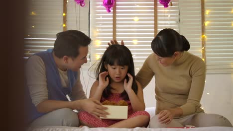Familia-asiática-feliz-celebrando-el-cumpleaños-de-la-hija-de-apertura-regalos-y-se-regocijan-en-cama.-Navidad,-celebración-de-cumpleaños.-Fiesta-de-año-nuevo.-Cámara-lenta.