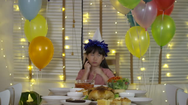 Traurig-wenig-asiatische-Mädchen-feiern-ihren-Geburtstag-allein-an-einem-Tisch-mit-einer-Torte-und-einer-Kerze,-Gäste-nicht-kommen.-Slow-Motion.