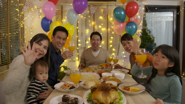 Familia-asiática-feliz-haciendo-videollamada-y-disfrutando-de-una-cena-de-Navidad-juntos-en-casa.