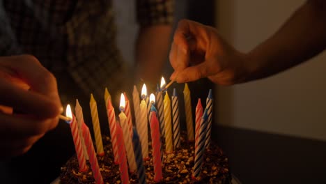 Male-and-female-lights-candles-on-tasty-birthday-cake.-Prepearing-for-party