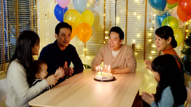 Asiatischer-Mann-bläst-Kerzen-auf-Geburtstagskuchen-auf-Party-mit-glücklich-Emotion.-Menschen-mit-Party-und-Feier-Konzept.-4K-Auflösung.