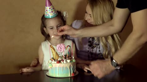 Mutter-und-Tochter,-die-Kerzen-auf-einem-Geburtstagskuchen-zu-zählen.-kleines-Mädchen-in-einem-festlichen-Hut-an-einer-Kinder-party