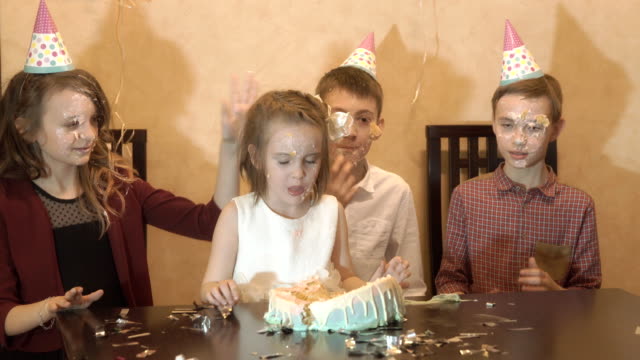 unbeschwerte-Kinder-auf-einer-Geburtstagsfeier.-Freunde-tunkte-Gesicht-in-die-Geburtstagstorte.