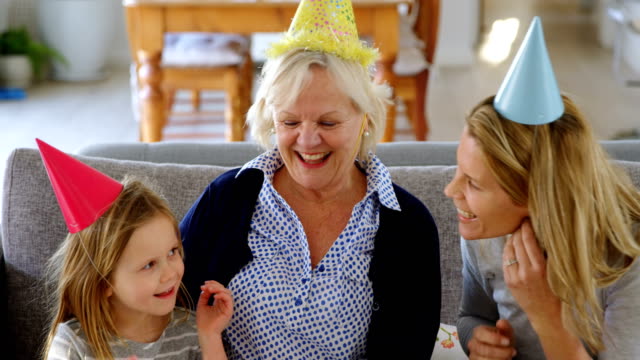 Múltiples-generaciones-familiares-celebrando-cumpleaños-en-sofá-4-k